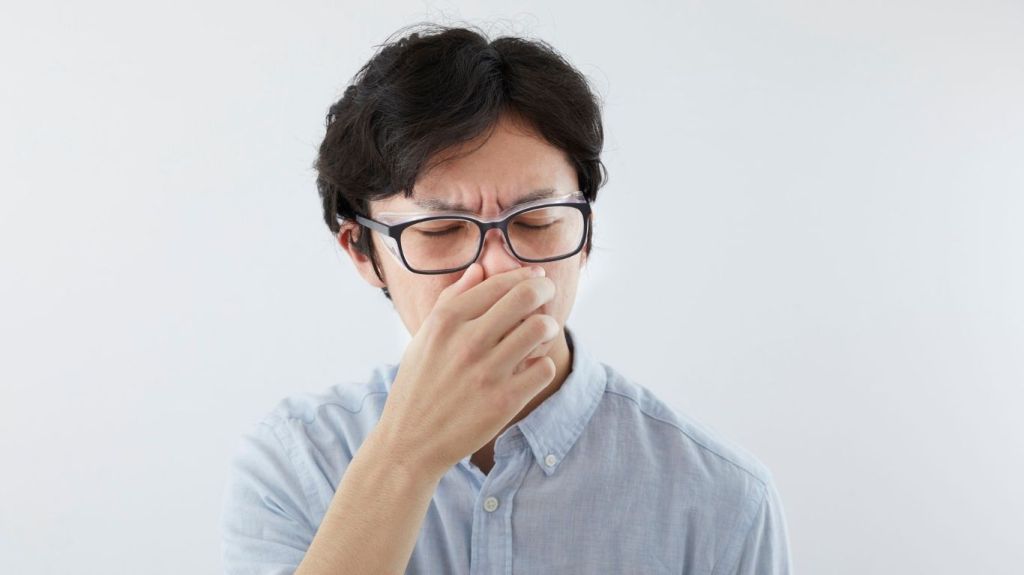Man pinching his nose not to hear the smell of a fart